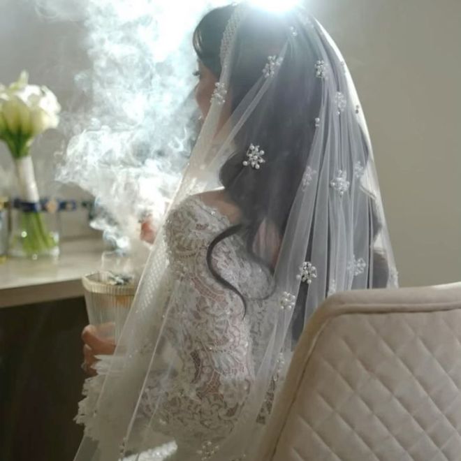 عروس سعودية ترتدي فستاناً أبيض وتمسك مبخرة يخرج منها
البخور ضمن طقوس الزواج