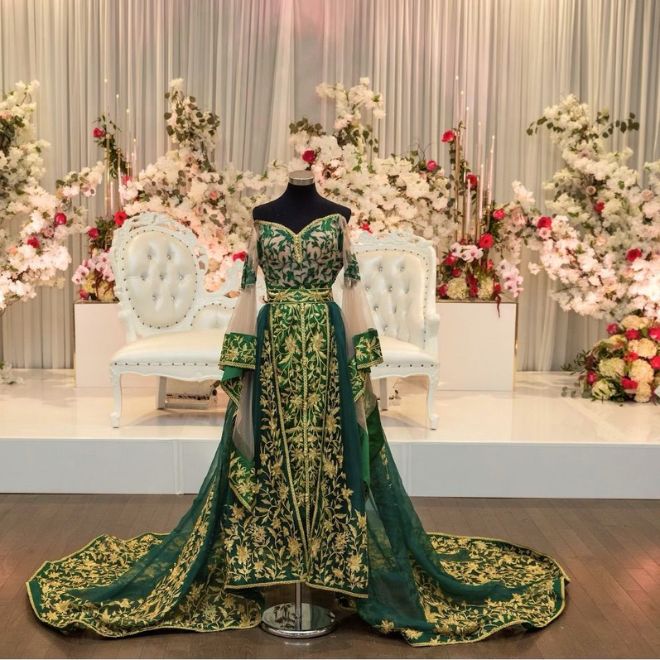 فستان غمرة سعودي مطرز باللونين الأخضر والذهبي معروض
أمام كوشة زفاف مزينة بالزهور