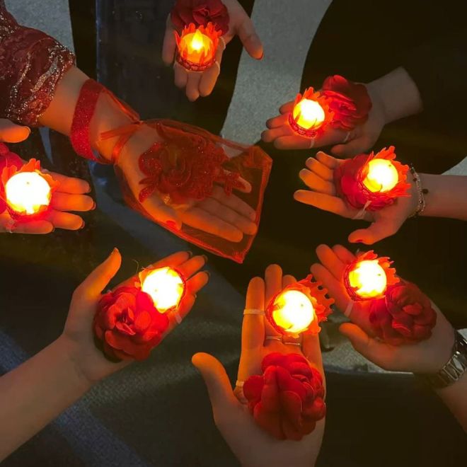 أيدي فتيات يحملن شموعاً مزينة بالورود الحمراء في دائرة
خلال ليلة الغمرة للعروس السعودية