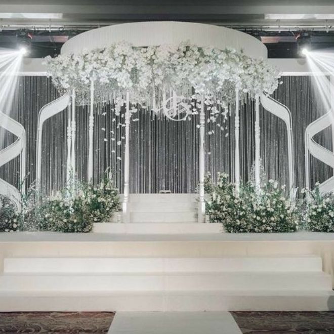 مسرح كوشة عروس فاخرة بإضاءة قوية وزهور بيضاء في قاعة
زفاف يوضح نموذج منصة واضحة للرؤية من طاولات الضيوف